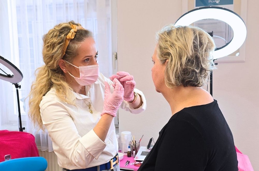 PMU Quereinsteigerin Evelyn während ihrer praktischen Übung in der Jamila’s Beauty Akademie. Sie trägt Handschuhe und eine Schutzmaske, während sie eine Lippenpigmentierung bei einer Kundin vorzeichnet. Perfektion, Präzision und Leidenschaft – der Weg in eine neue Karriere im Permanent Make-up.